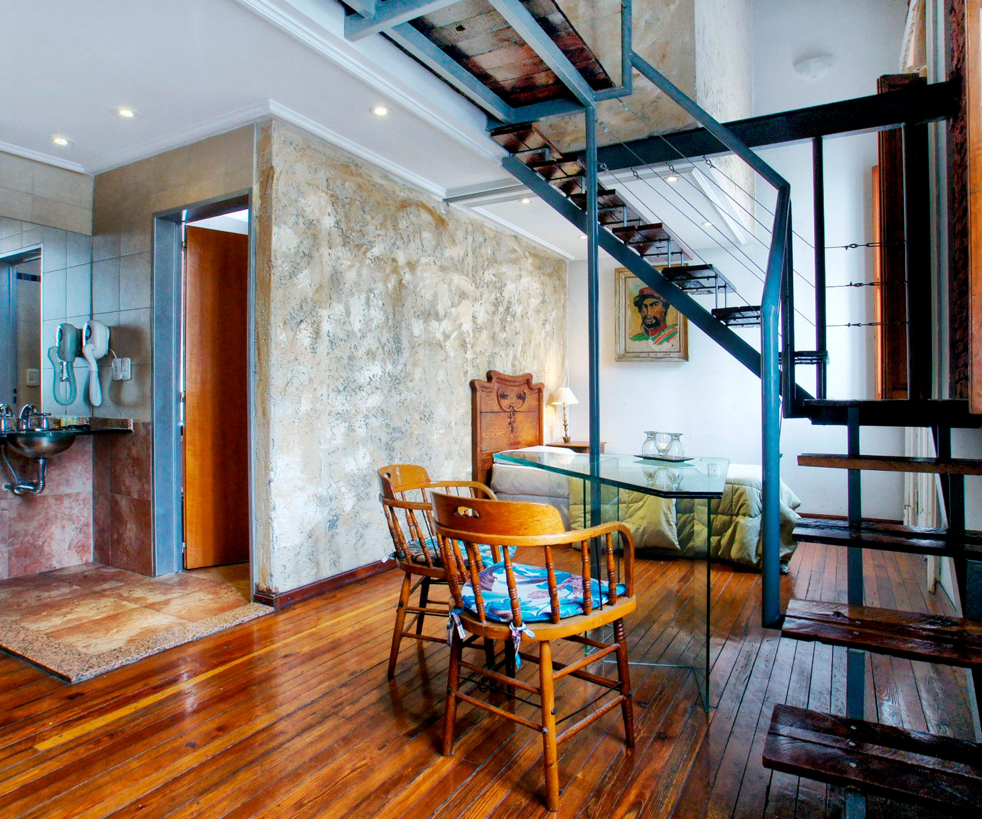 Suite tipo loft con escalera en madera y mobiliario de época