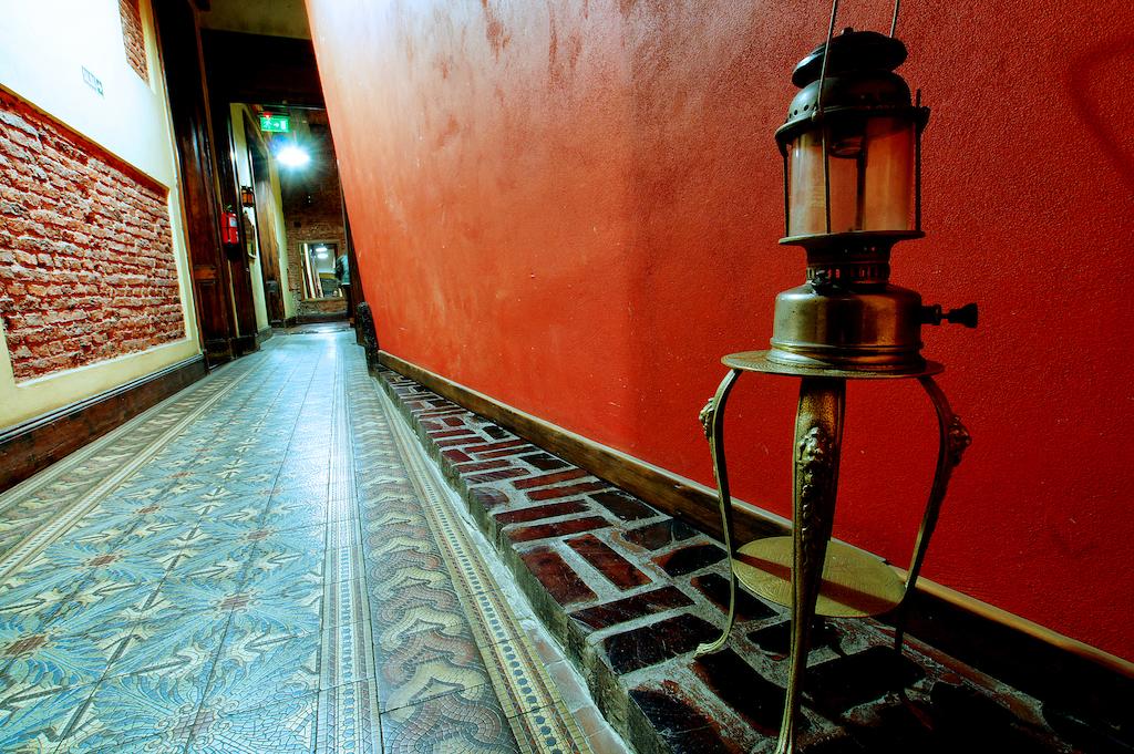 Galería interior con pisos calcáreos originales, ladrillo a la vista y farol antiguo de bronce