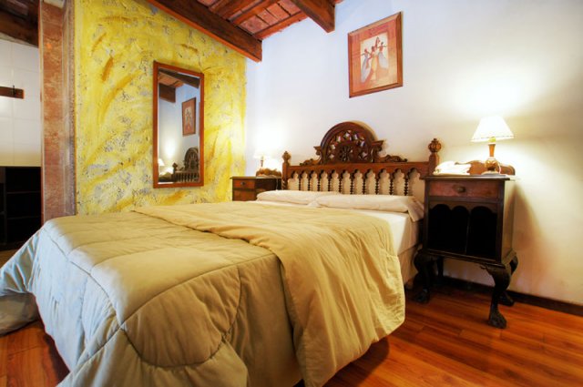 Habitación Suite con bovedillas, cama matrimonial y cabecera tallada